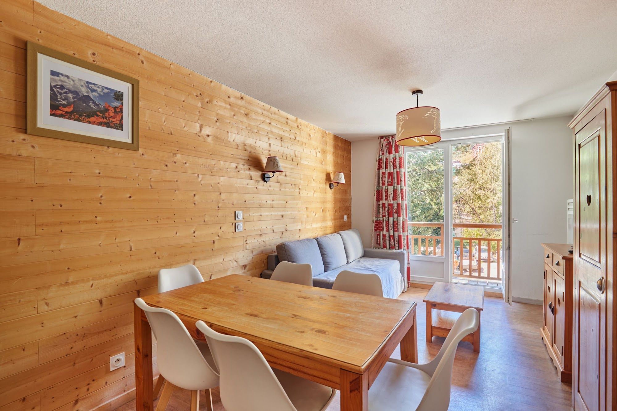 Une pièce aux murs lambrés, comprenant une table à manger, des chaises, un canapé et offrant une vue sur l’extérieur.