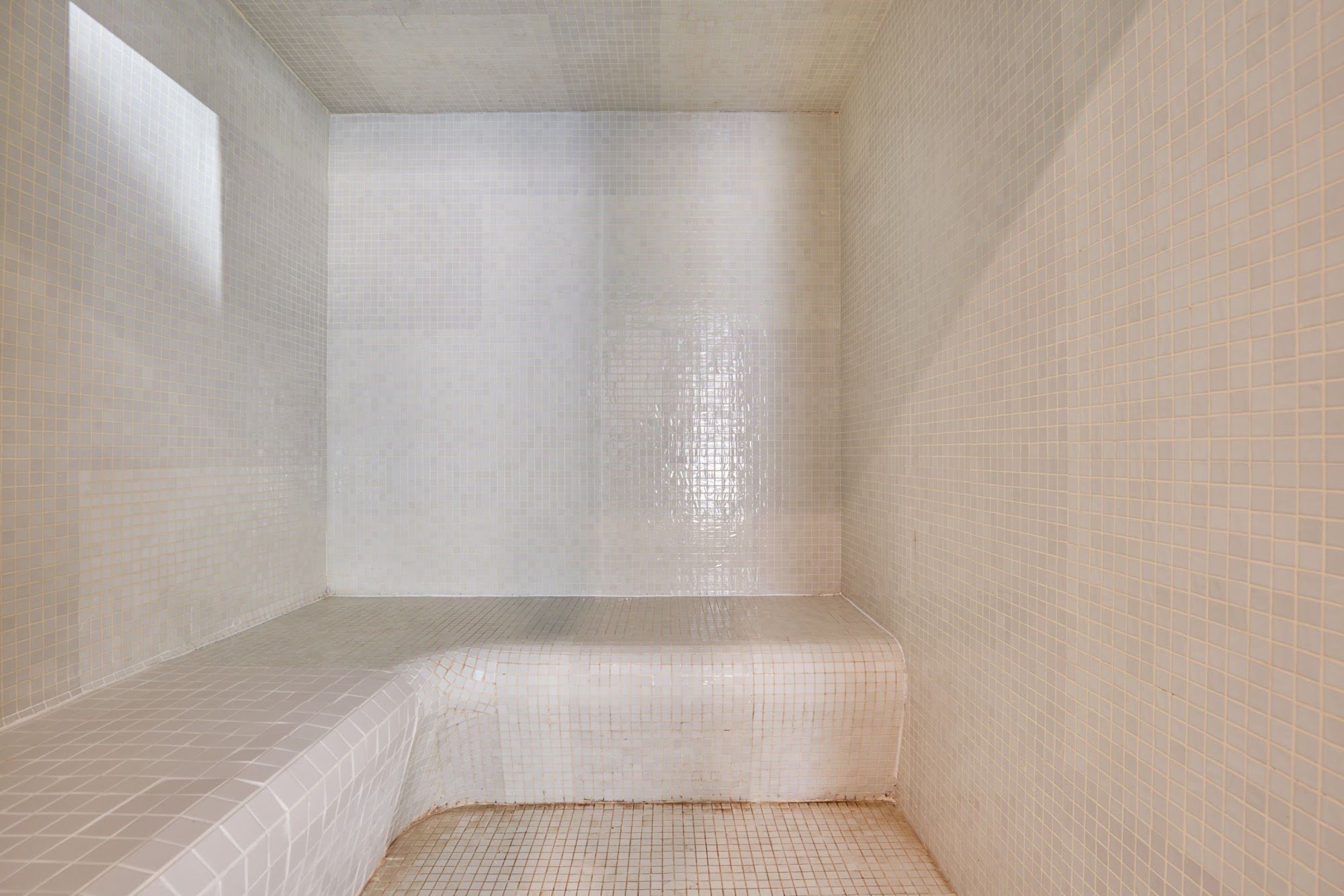 Un baño con baldosas, que incluye una zona de ducha, un lavamanos y un inodoro.