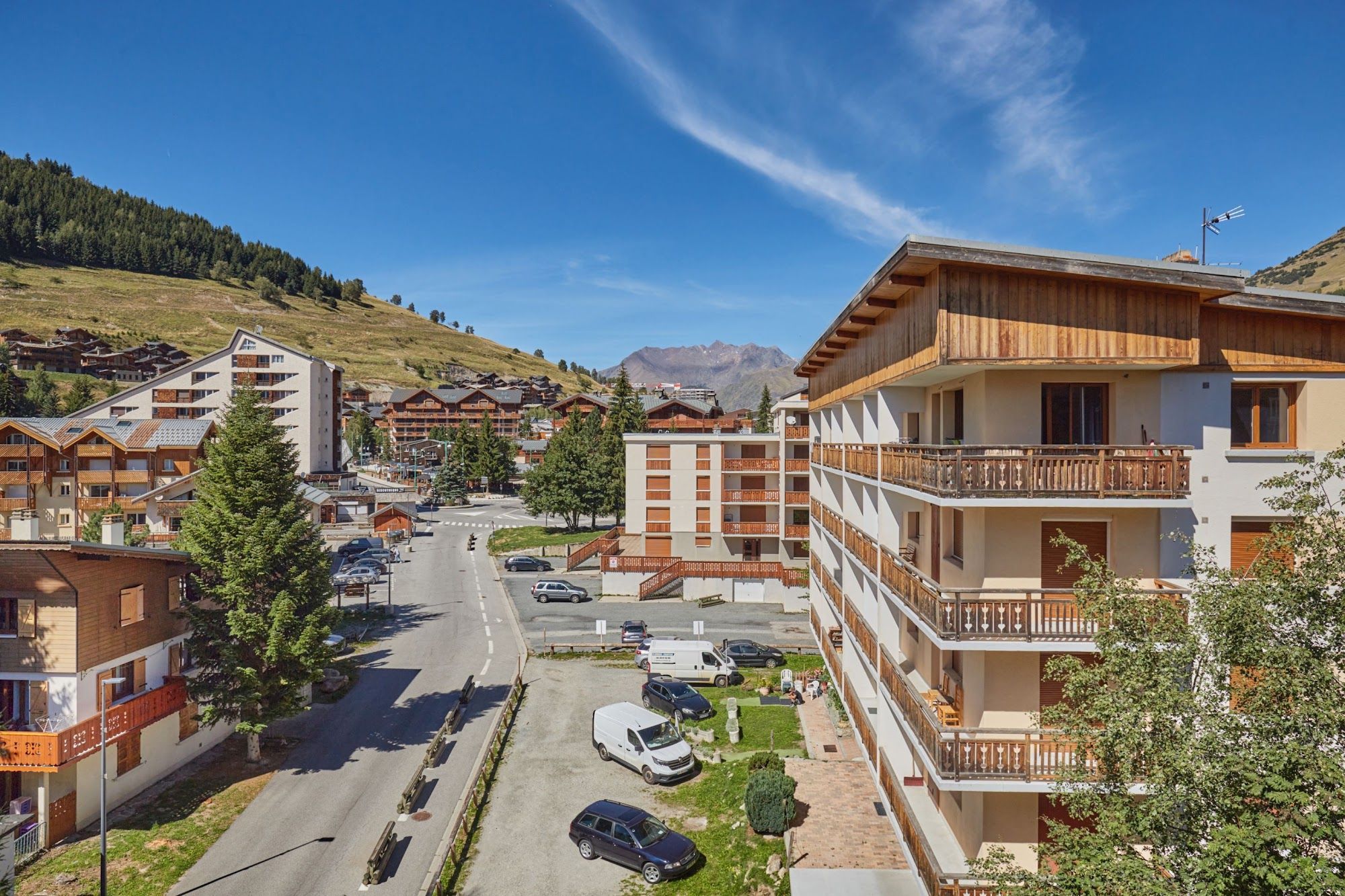 A residential area with multi-story buildings, a main road, and a mountain in the background.