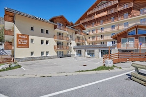 A multi-story hotel with wooden balconies and a sign indicating 'Odalys L'Ours Blanc.'