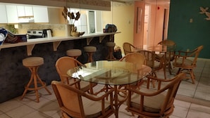 A dining area with a round glass table surrounded by wicker chairs. - Right On the Beach !  Vacation Condo ! (Panama City Beach)