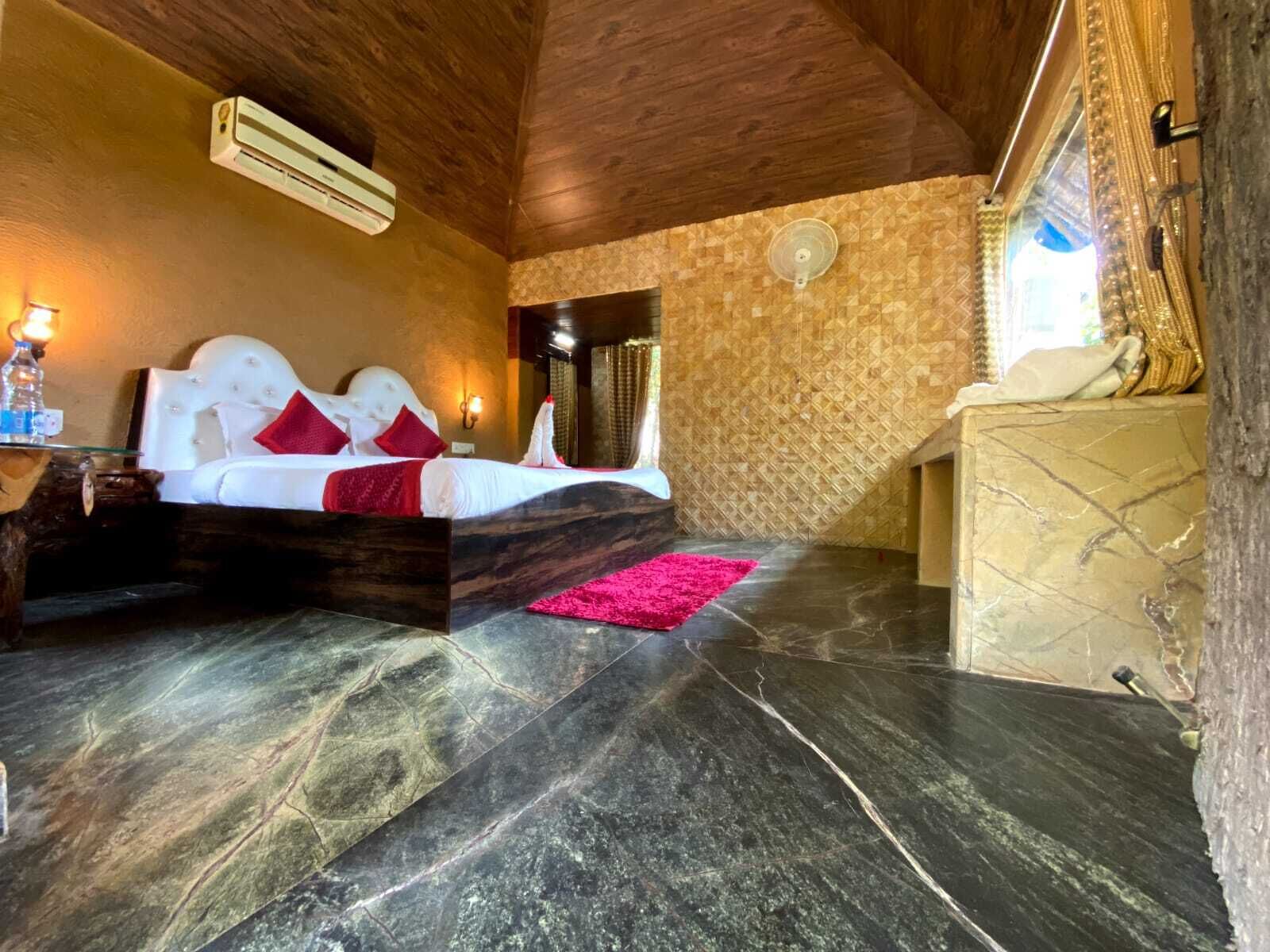 Un dormitorio con cama, mesita de noche, aire acondicionado de pared y ventana con cortinas.