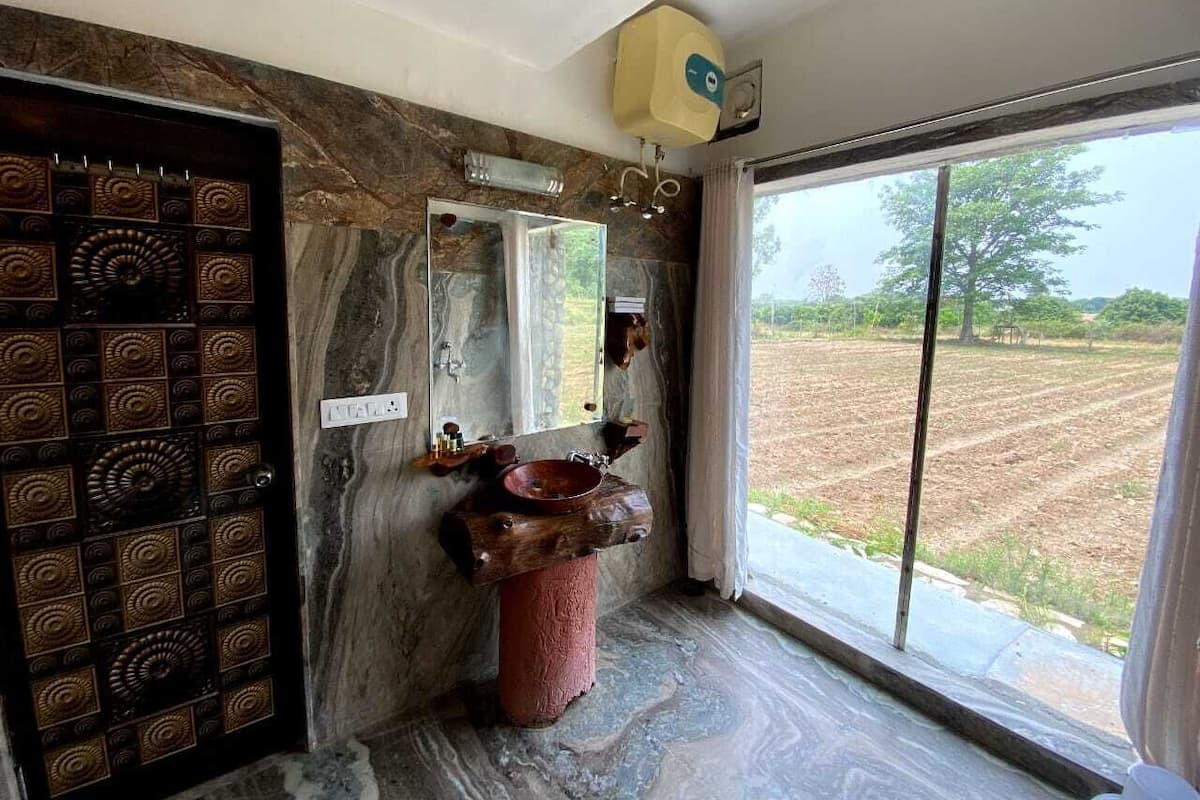 Un baño con pared de mármol, lavamanos de madera y un espejo grande.
