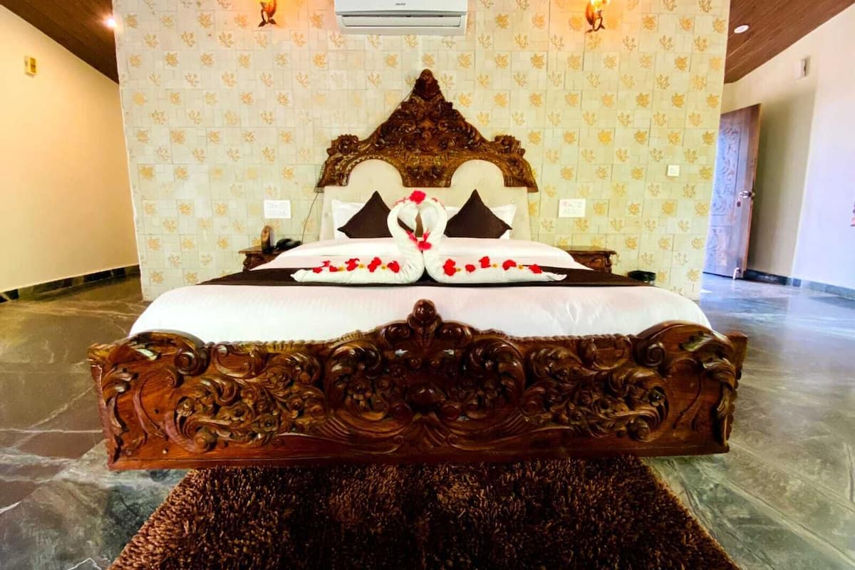 Una cama grande de madera ricamente tallada con un cabecero floral, dos lámparas de pared y un equipo de aire acondicionado encima.