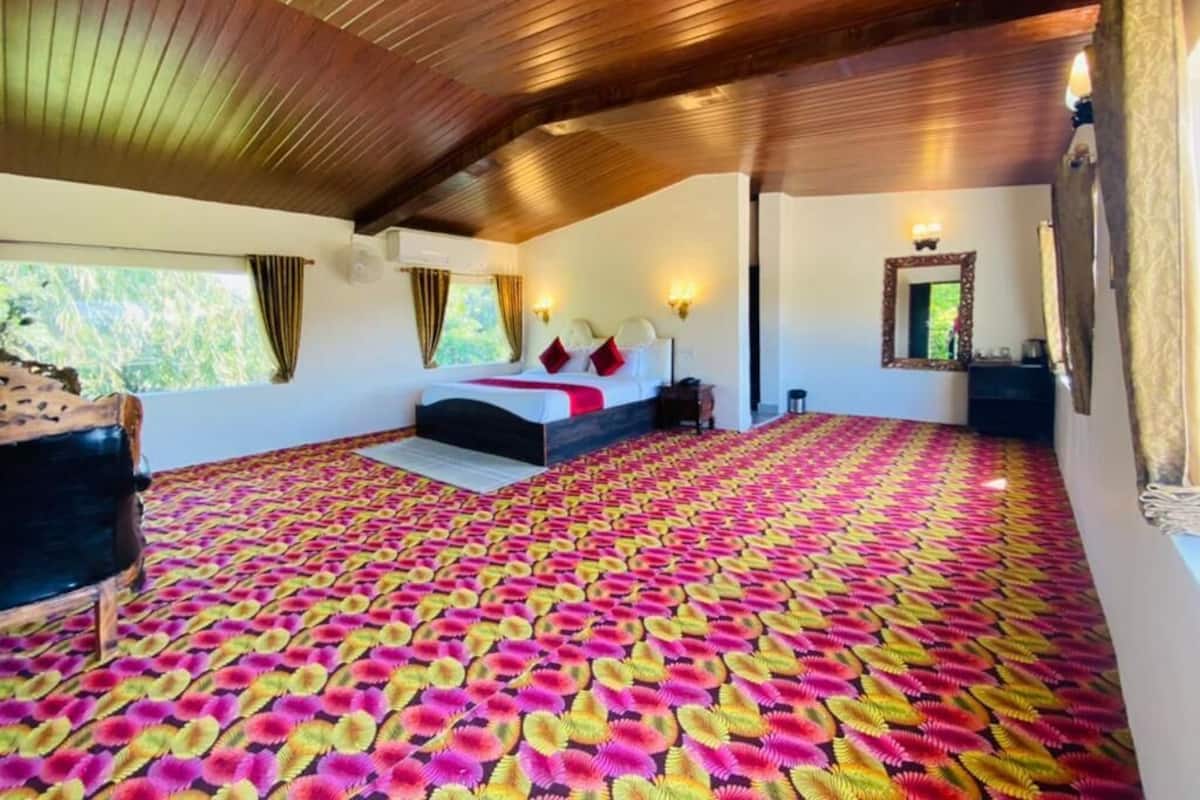 Un dormitorio amplio con una cama grande, techo de madera y alfombra estampada.