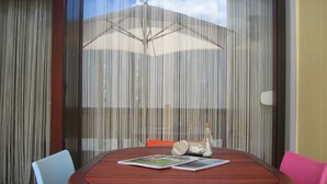 Une table ronde en bois, avec deux chaises, une bouteille et quelques magazines dessus.
