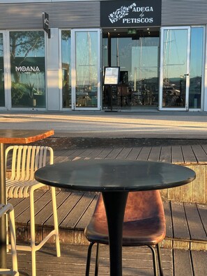 A restaurant with outdoor seating, a sign for 'A DEGA de PETISOS,' and a 'MOANA MARINA' sign.