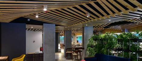 A modern interior with wooden beams, a blue sofa, yellow chairs, and a green plant wall.