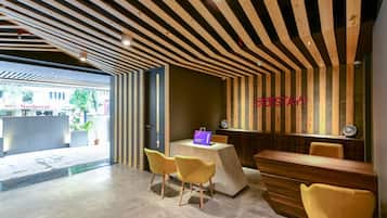 Un área de recepción con techo de listones de madera, un mostrador de recepción y tres sillas amarillas.