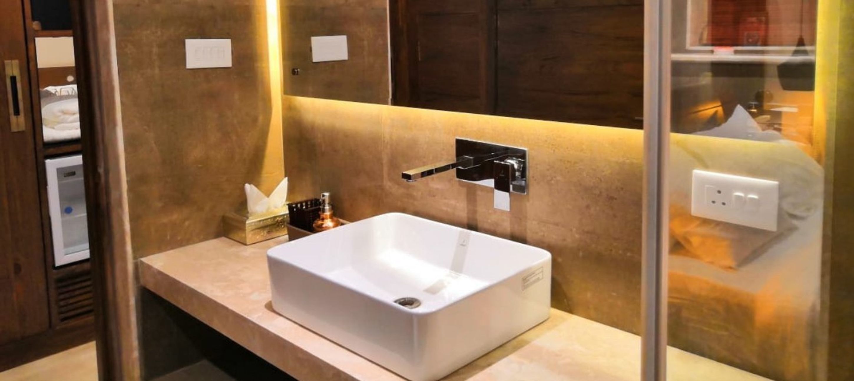 A modern bathroom with a white sink, a towel dispenser, and a mirror.