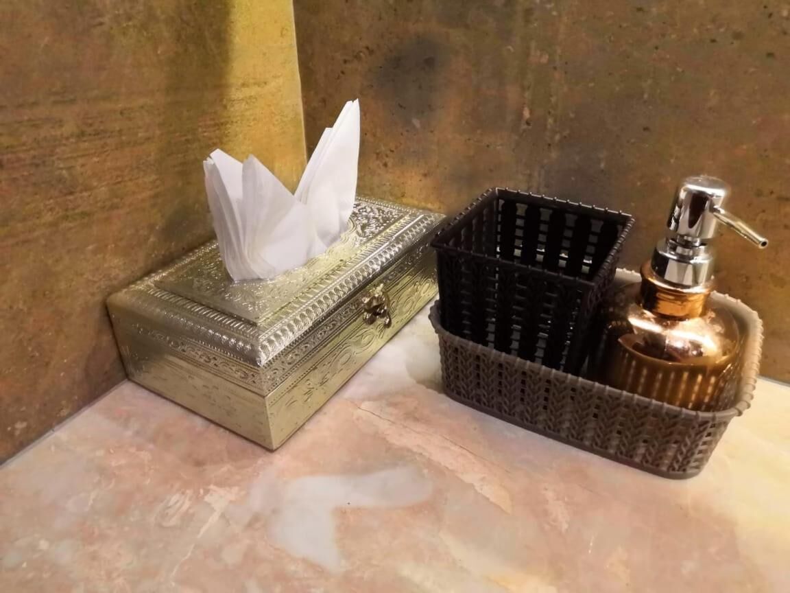 Une boîte de mouchoirs et un distributeur de gel hydroalcoolique sur une surface en marbre.