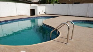 A swimming pool with a curved edge and a metal ladder.