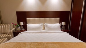 A hotel room with a large bed, two bedside tables with lamps, a chair, and a nightstand with a vase of flowers. - Premium apartment on the Beach Oazis Hotel (Kobuleti)