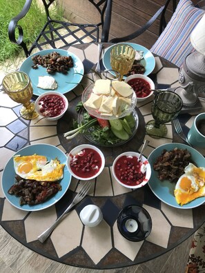 Una mesa servida con varios platos, incluyendo huevos, carne y queso, rodeada de cuencos y vasos.