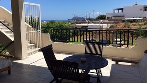 Un balcon avec vue sur la mer, une table avec des chaises et un escalier.