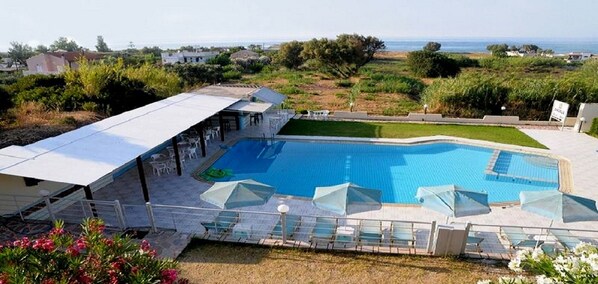 A swimming pool with a view of the sea, surrounded by greenery and a covered seating area. - Andysgardens (Platanias)