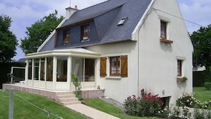 A two-story house with a covered porch, a chimney, and a garden with flowers. - Chambres d'hotes de la Ville Patouard (Tremereuc)