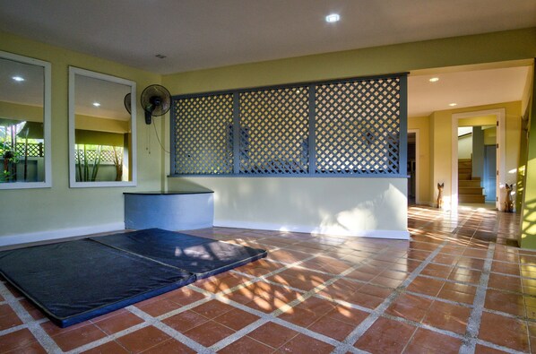 A room with a tiled floor, a mat, a fan, and a partition wall.