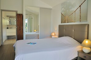 A bedroom with a large bed, bedside lamps, a mirror, and a wall-mounted artwork of a bridge. - Maison Ganttipiena (Ahetze)