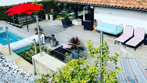 Uma área residencial com piscina, área de estar ao ar livre e um guarda-sol vermelho.