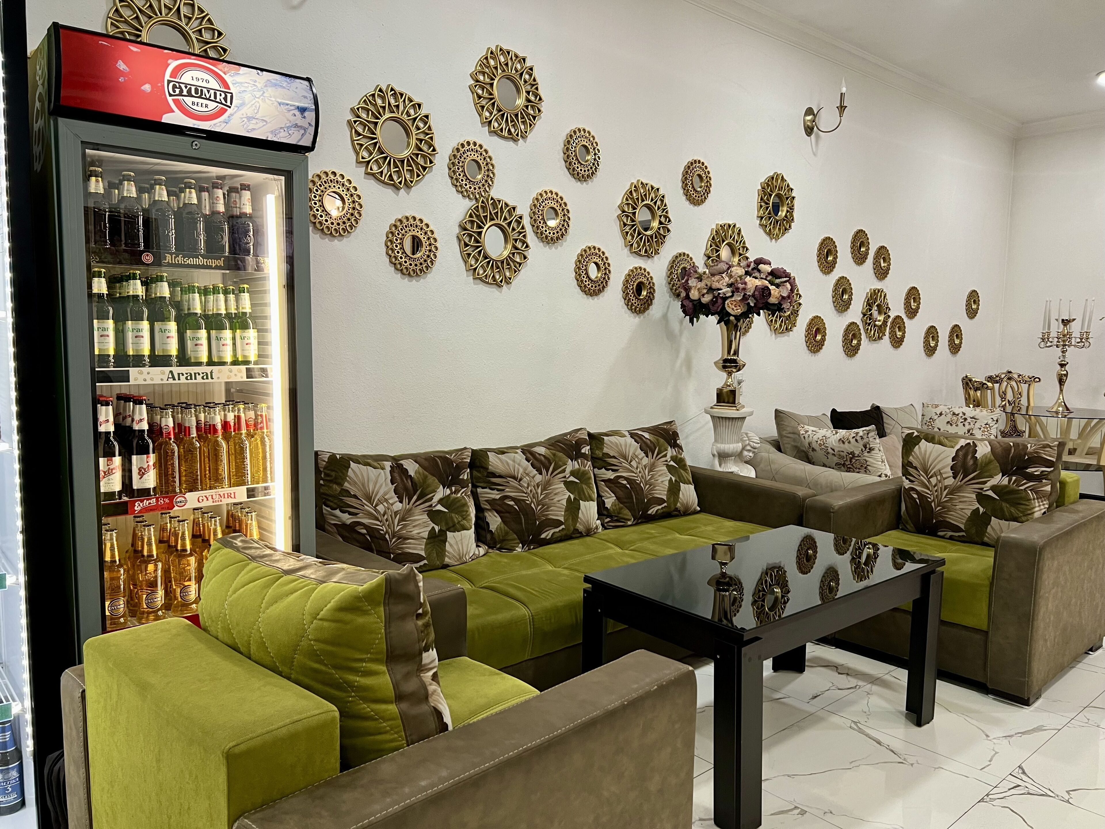 A living room with green sofas, a glass coffee table, and a wall decorated with circular mirrors.