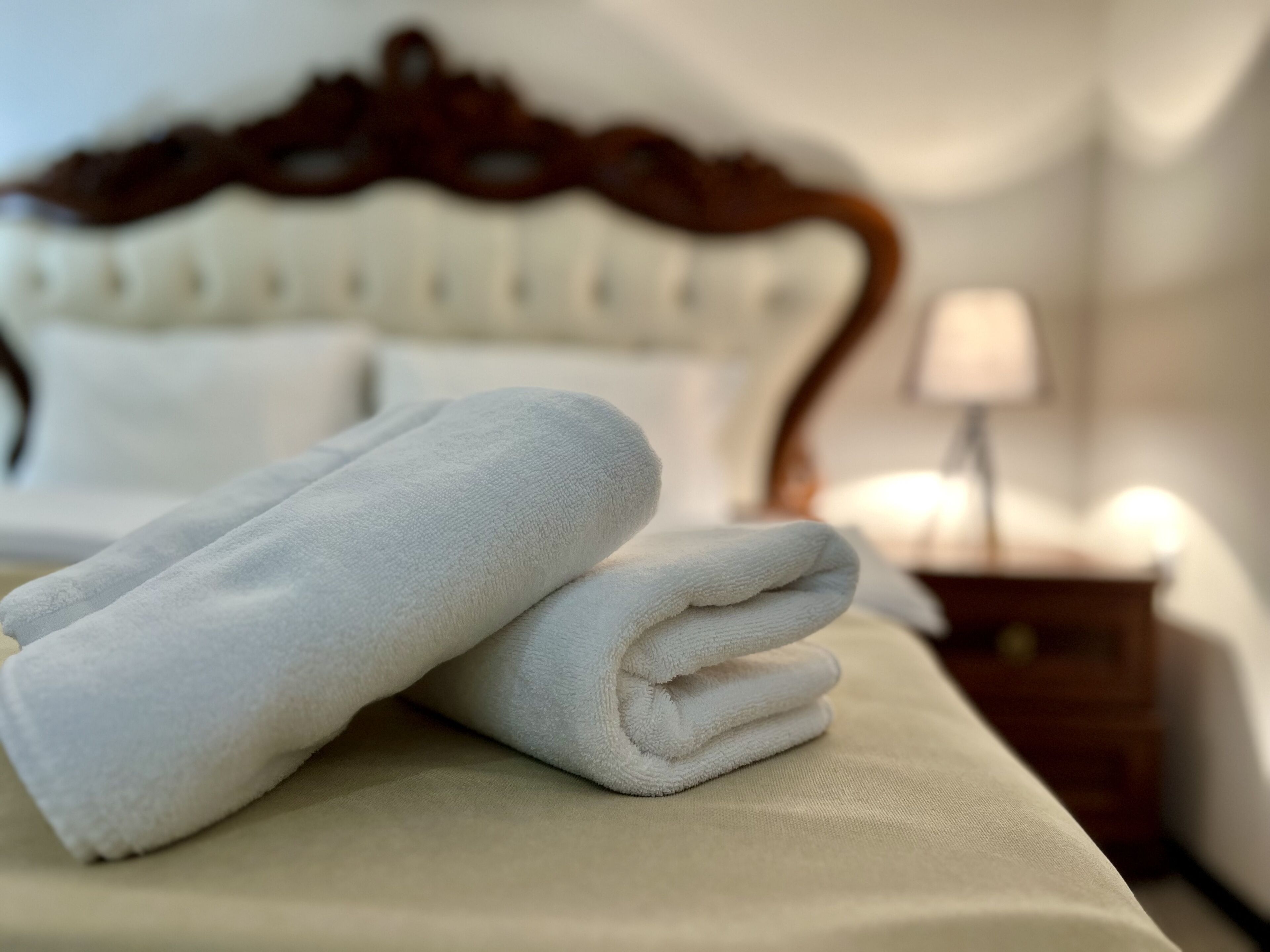 A neatly made bed with a white duvet and a folded white towel on the bed.