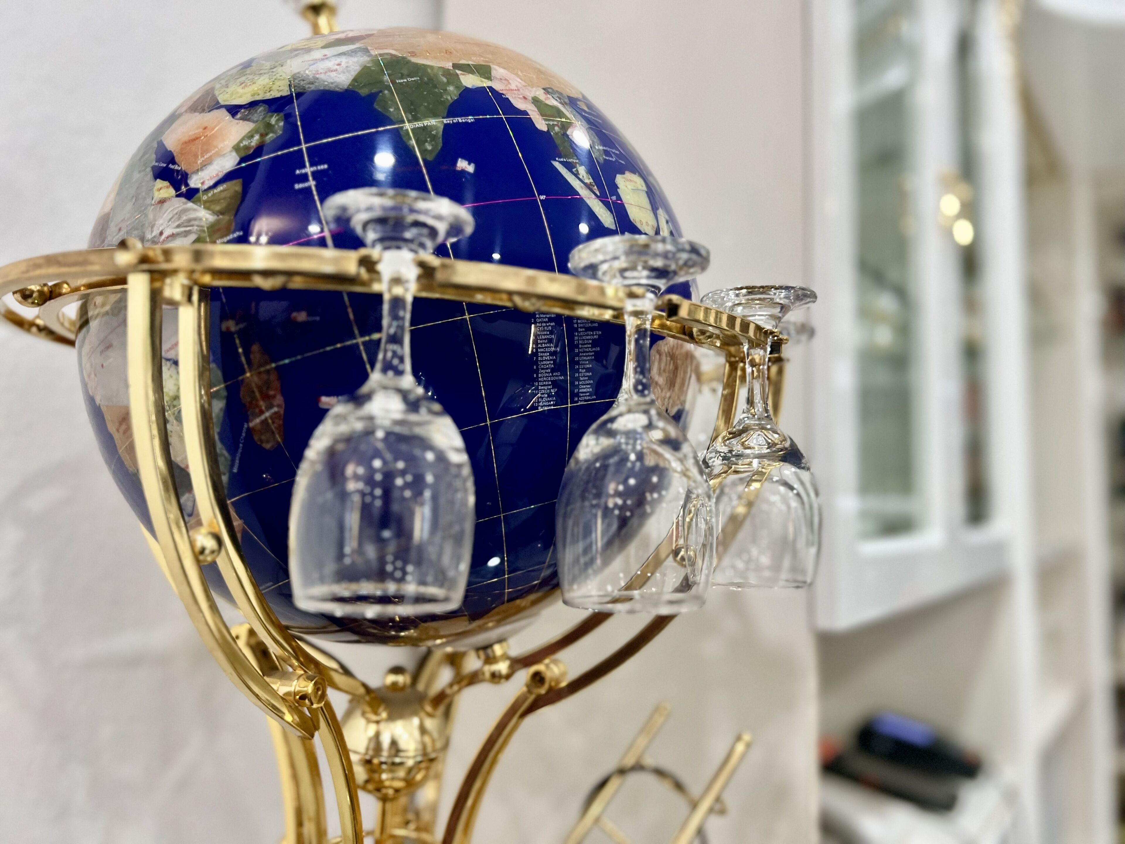 A globe with a golden stand and three clear glass vases.