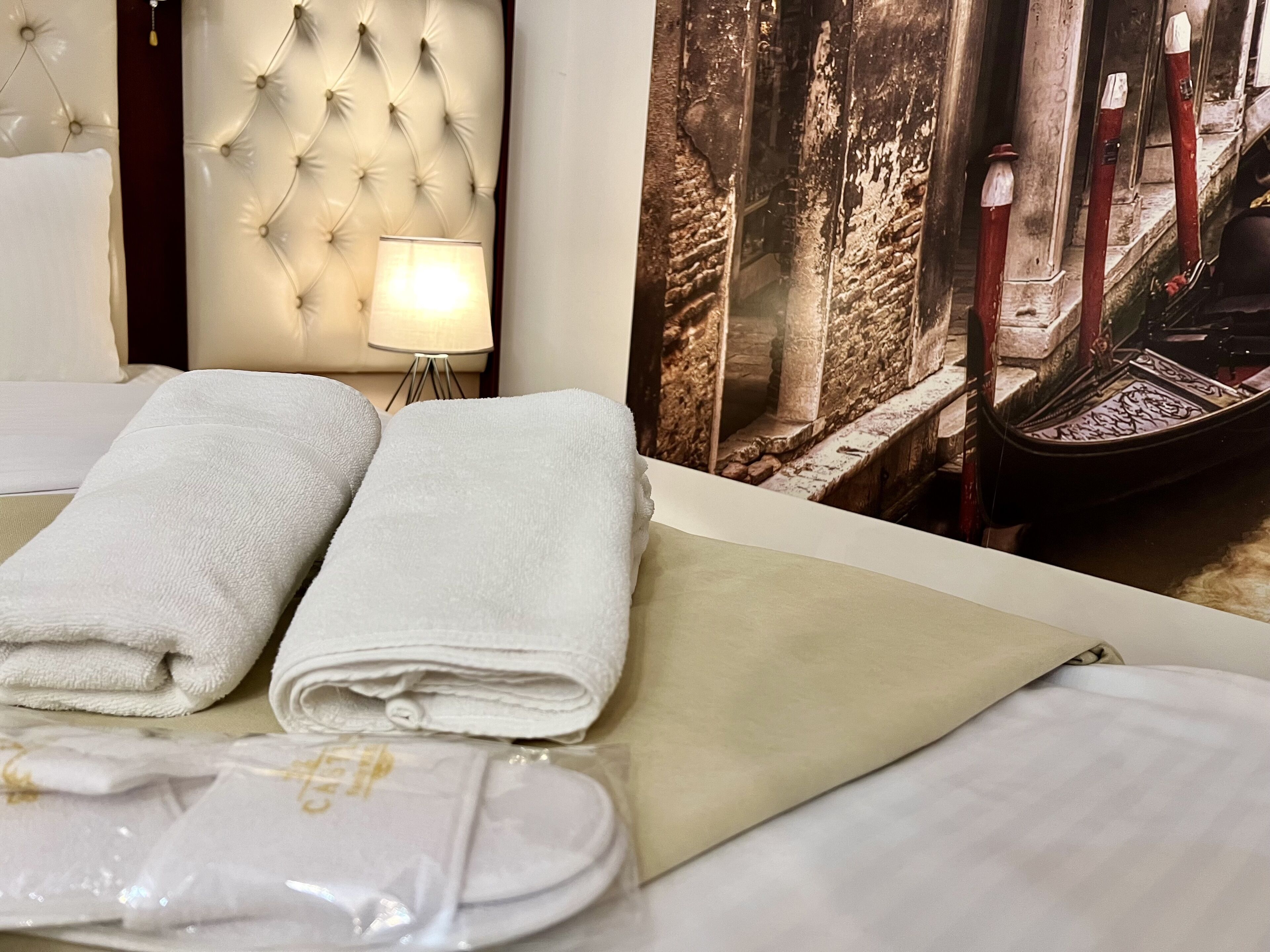 Una cama bien hecha con toallas blancas dobladas y una bolsa de plástico.
