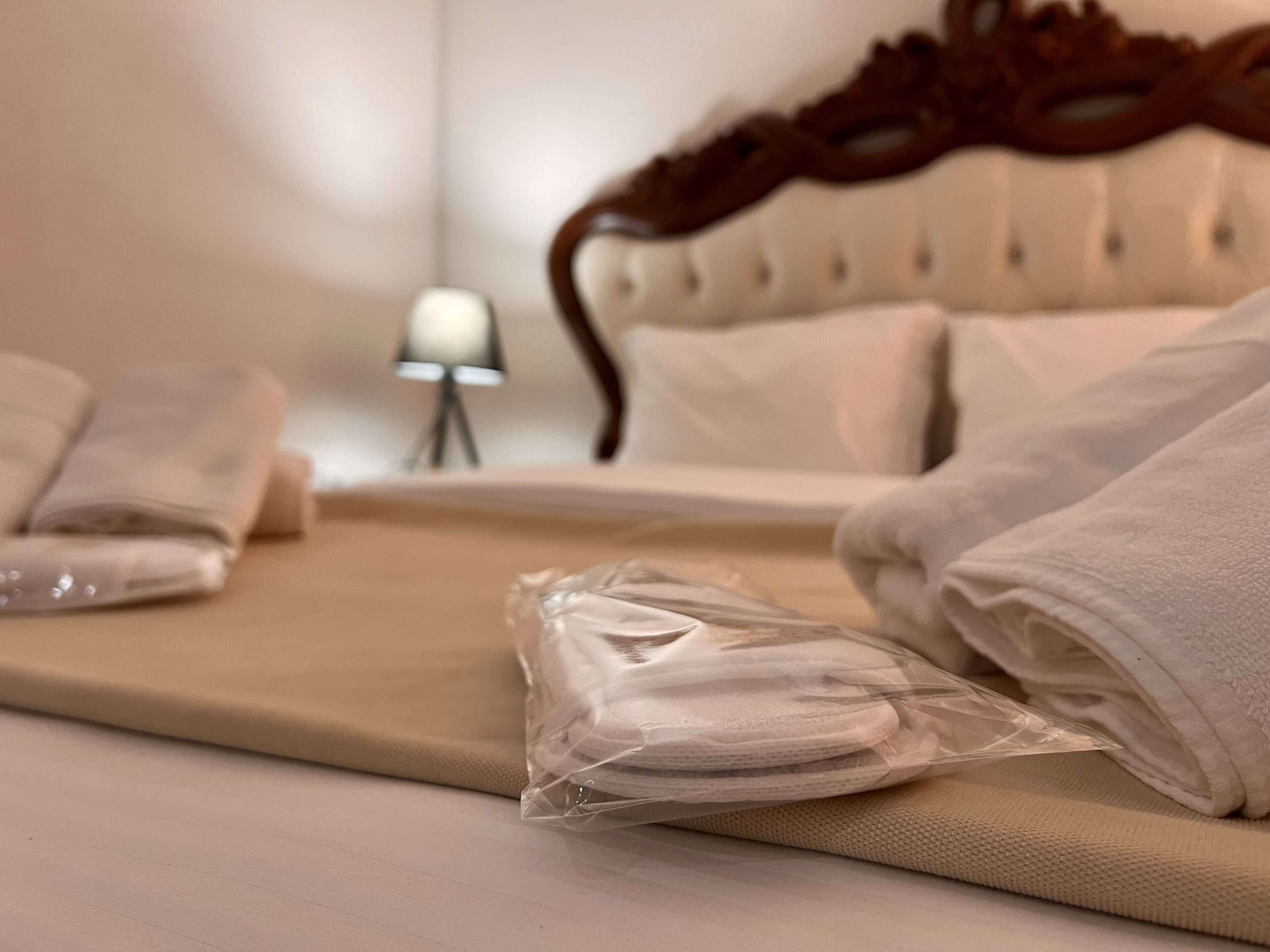 Una cama bien tendida con toallas dobladas y una bolsa de plástico con toallas adicionales.