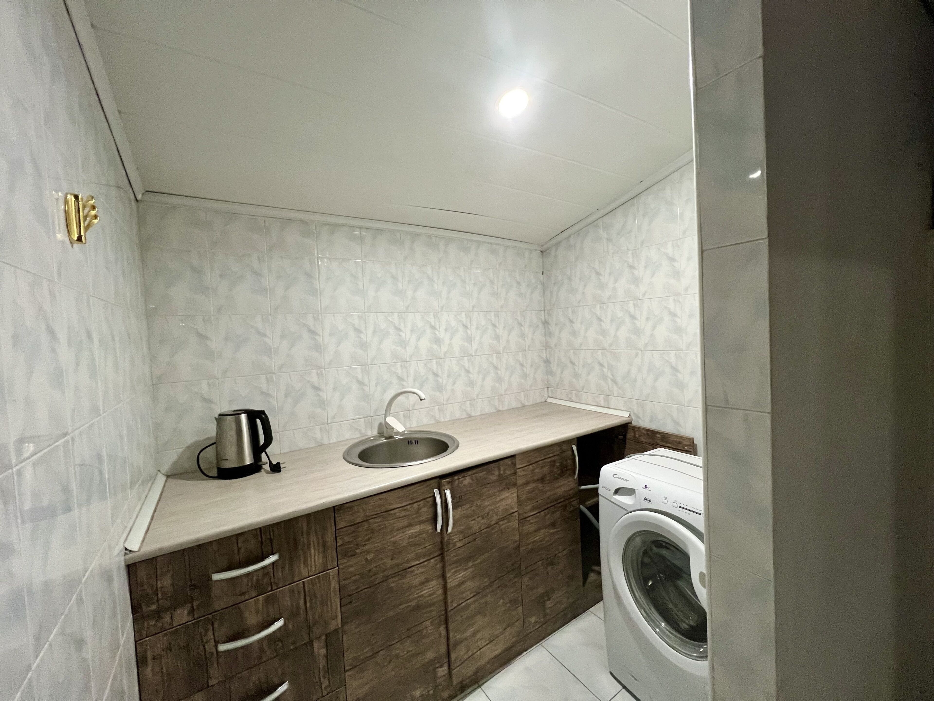 A compact kitchen with a sink, a coffee maker, and a washing machine.