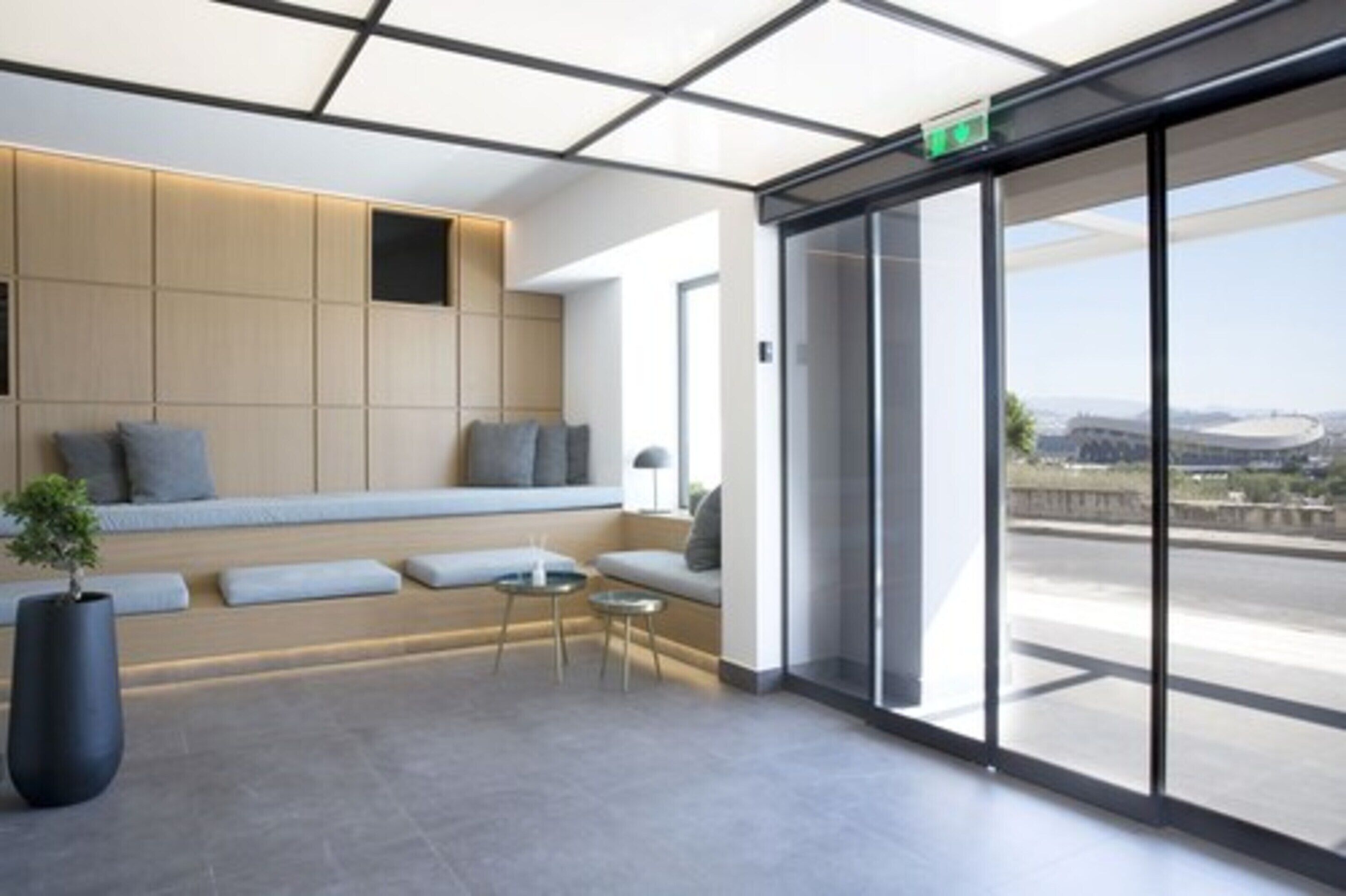 Eine moderne Lobby mit Sitzgelegenheit, einer Glastür zum Außenbereich und Blick auf die Stadtlandschaft.