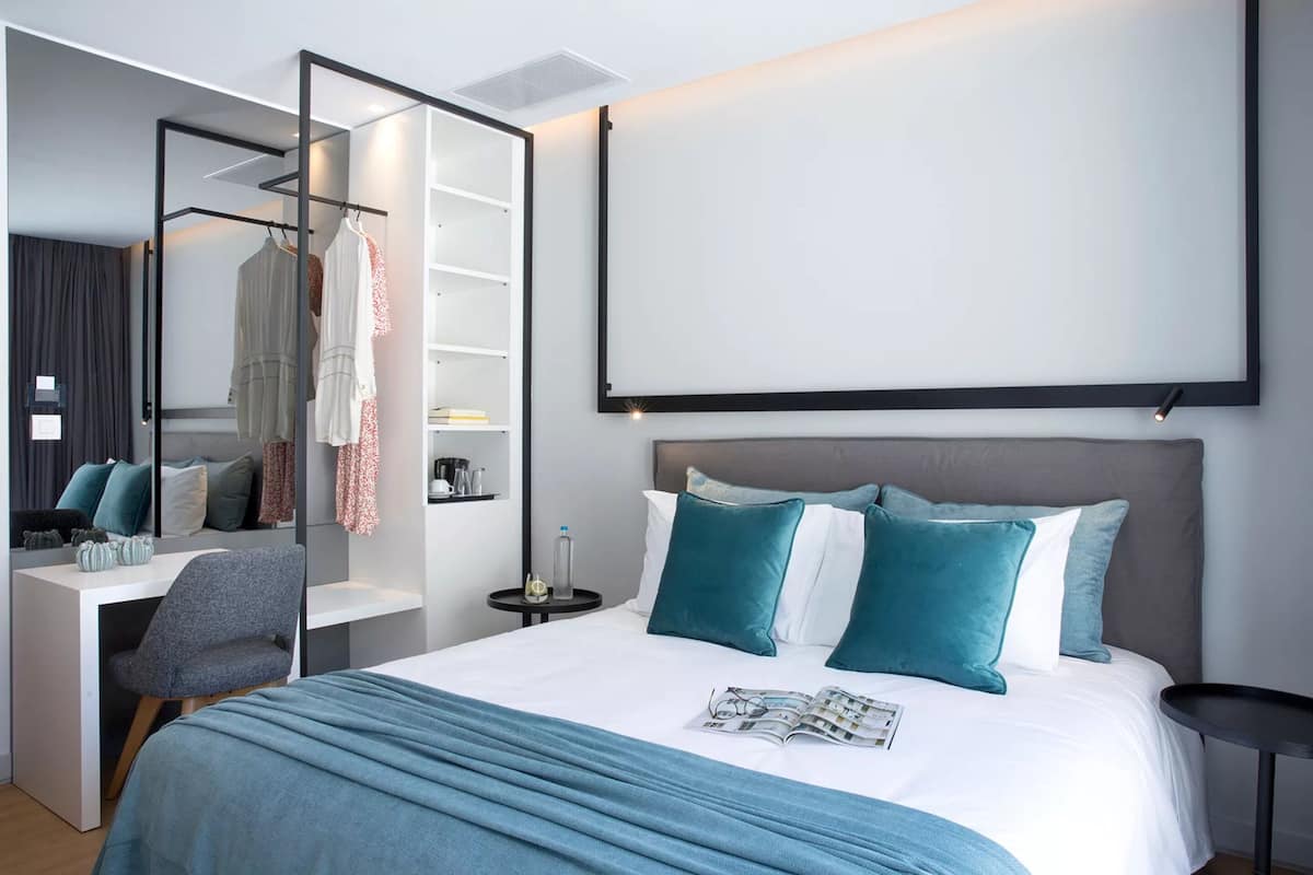 Una habitación de hotel moderna con una cama grande, un escritorio y un armario.