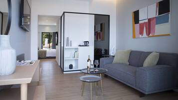 A modern living room with a grey sofa, a coffee table, and a dining area with a white table and a vase.