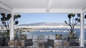 Un espacio de estar techado al aire libre con vista a un puerto deportivo y al paisaje urbano.