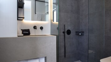A modern bathroom with a large mirror, a vanity with a makeup towel, and a shower with a glass door.