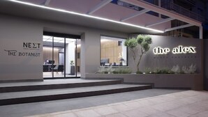 Una entrada moderna de edificio con señalización que indica 'The Botanist' y 'The Alex'.