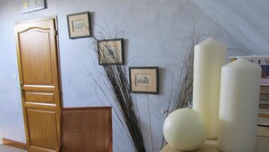 A room with a wooden door, a wicker chair, and a table with two white candles. - Le Champ du Pre (Gievres)