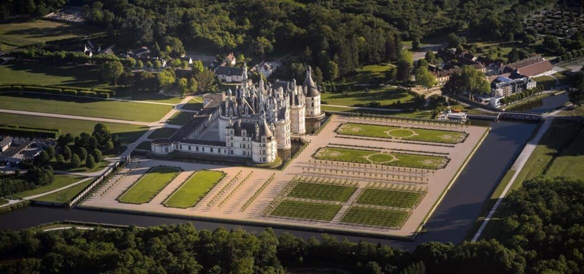 An aerial view of a castle with a formal garden and a moat.