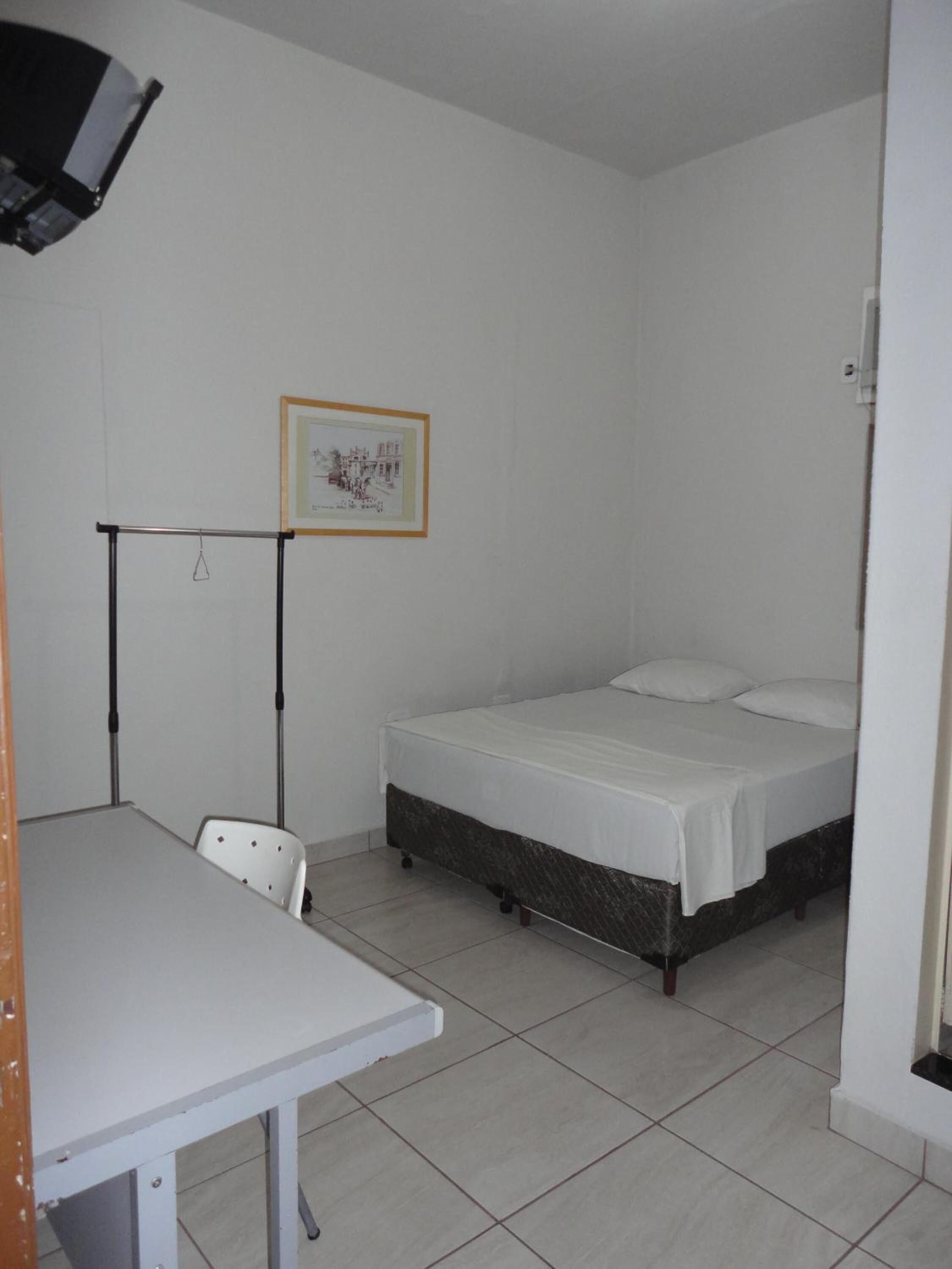 Ein kleines, sauberes Zimmer mit einem Einzelbett, einem Schreibtisch und einem Stuhl.