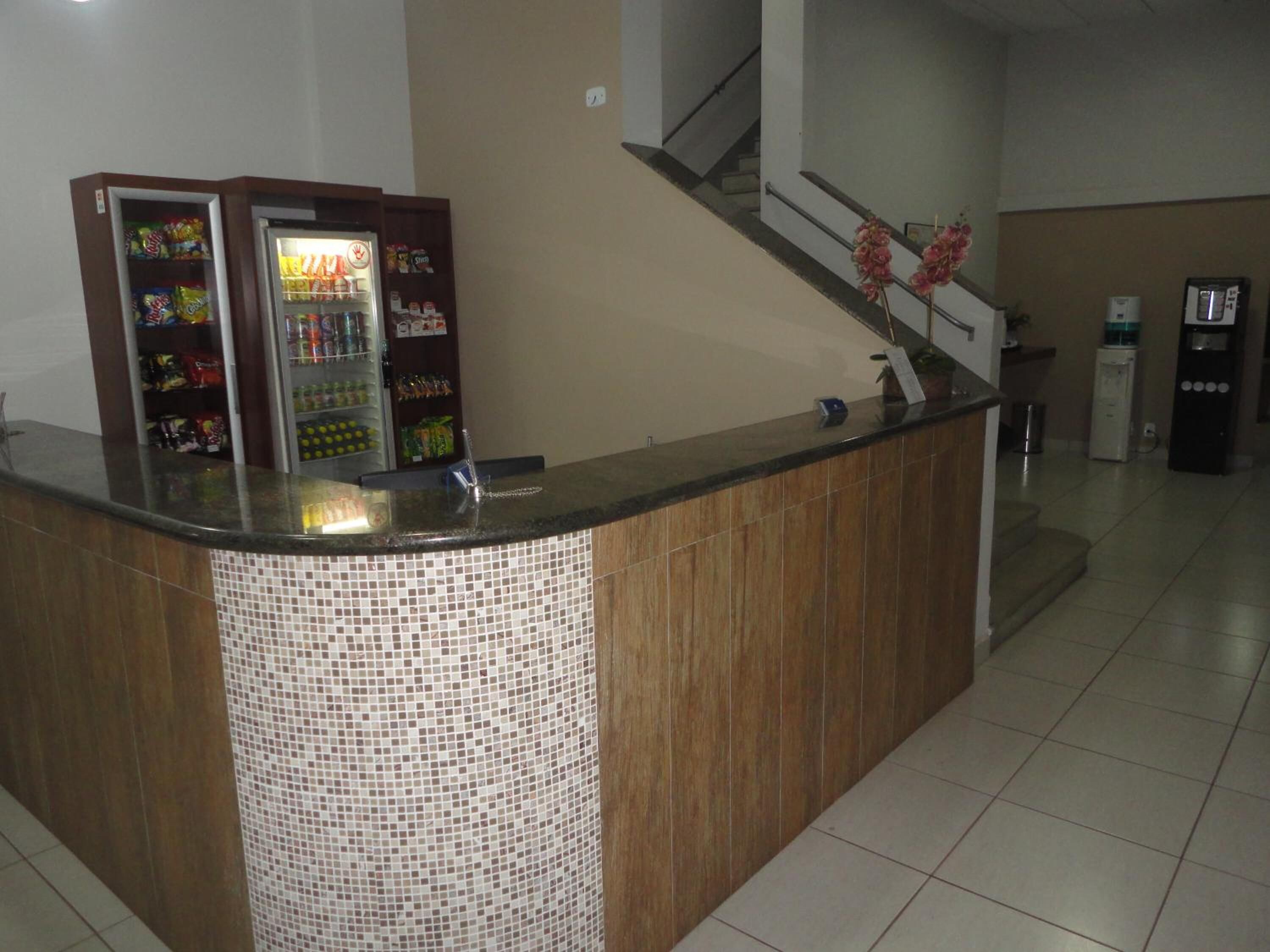 Zona de recepción con mostrador, máquinas expendedoras, una escalera y dispensador de agua.