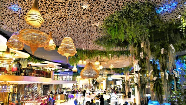A spacious indoor area with hanging wicker chandeliers, a central seating area, and a green wall with hanging plants. - OYO 225 Premier Place Hotel (Bangkok)
