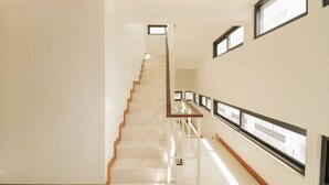 A staircase with a wooden handrail and a white wall with framed pictures. - OYO 225 Premier Place Hotel (Bangkok)