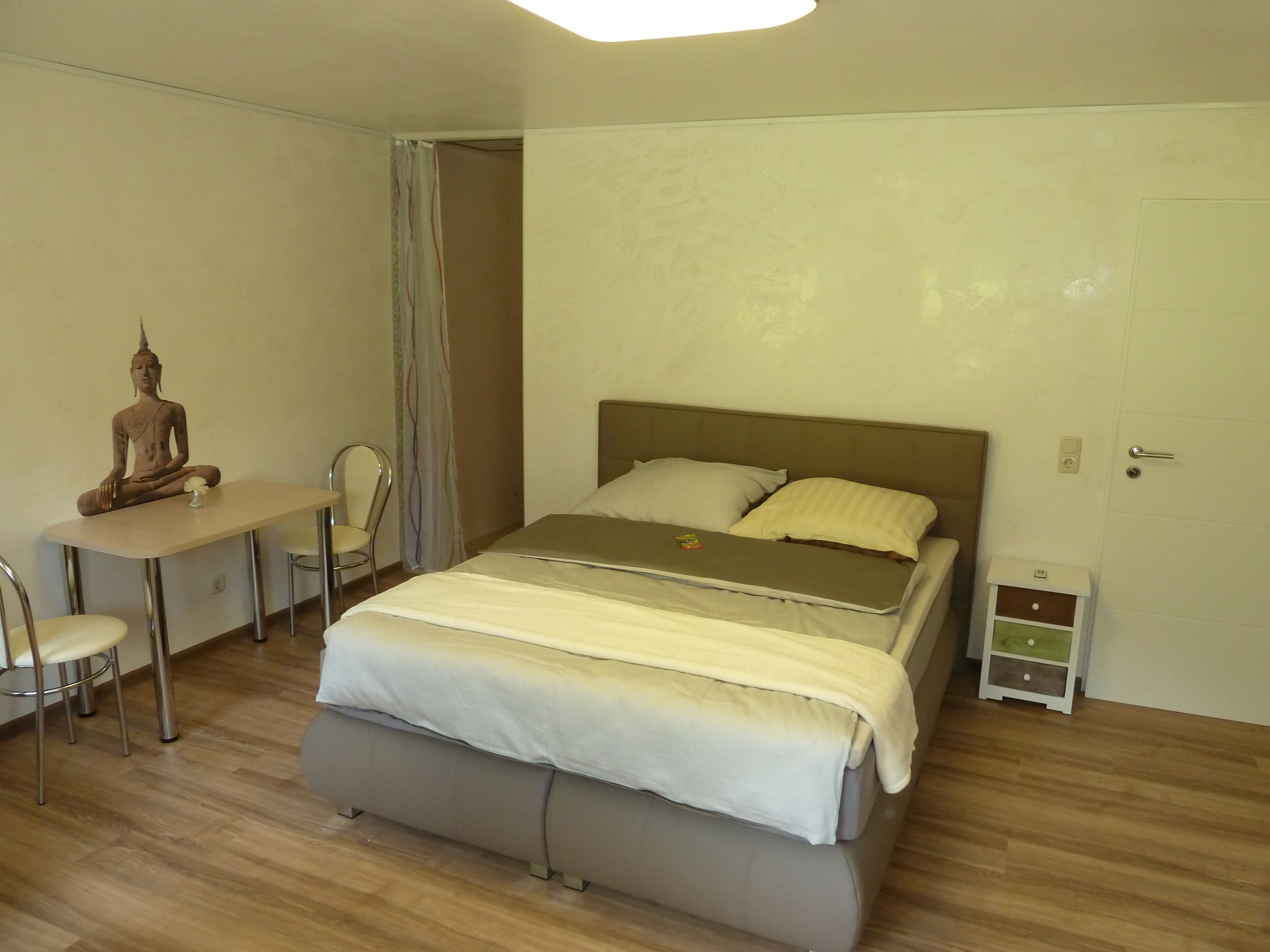 Un dormitorio con una cama, un escritorio, una silla y una estatua.