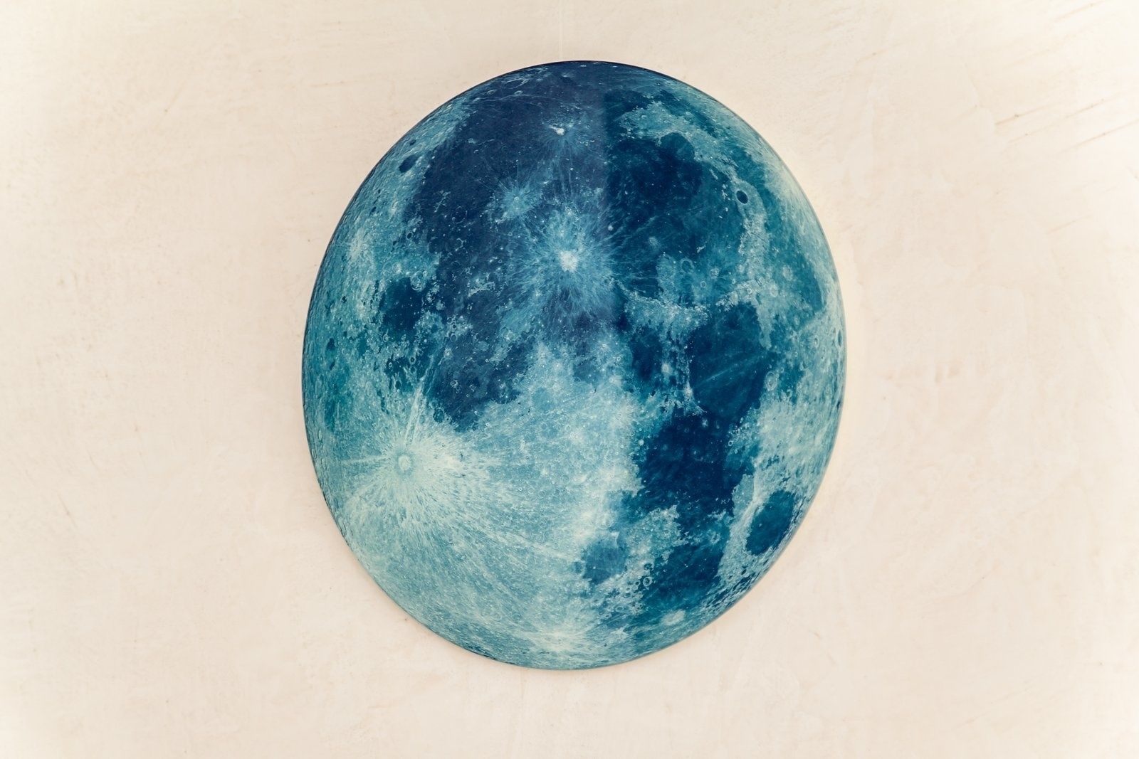 Un objeto redondo y ovalado con superficie texturizada, que recuerda a un cuerpo celeste, posiblemente una luna o planeta, sobre un fondo uniforme.