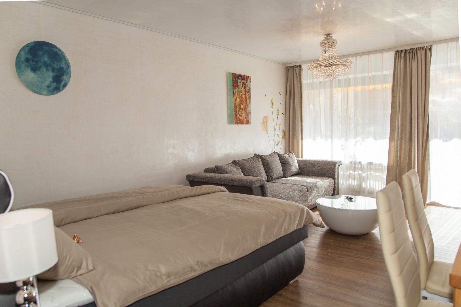 A modern hotel room with a bed, a sofa, a coffee table, and a chair.