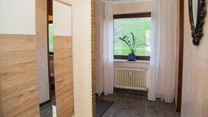 A hallway with a wooden door, a radiator, and a window with a plant. - Ferienwohnung Royal (Bad Toelz)