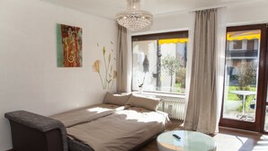 A modern bedroom with a bed, a small table, and a window with curtains. - Ferienwohnung Royal (Bad Toelz)