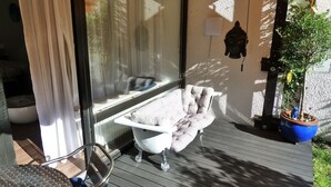 A spa area with a bathtub, a chair, and a potted plant. - Ferienwohnung Royal (Bad Toelz)