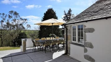 An outdoor patio with a stone wall, a table with chairs, and a large umbrella.