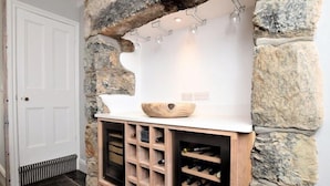 A wine cellar with a stone arch, wine racks, and a wooden bowl on a shelf.